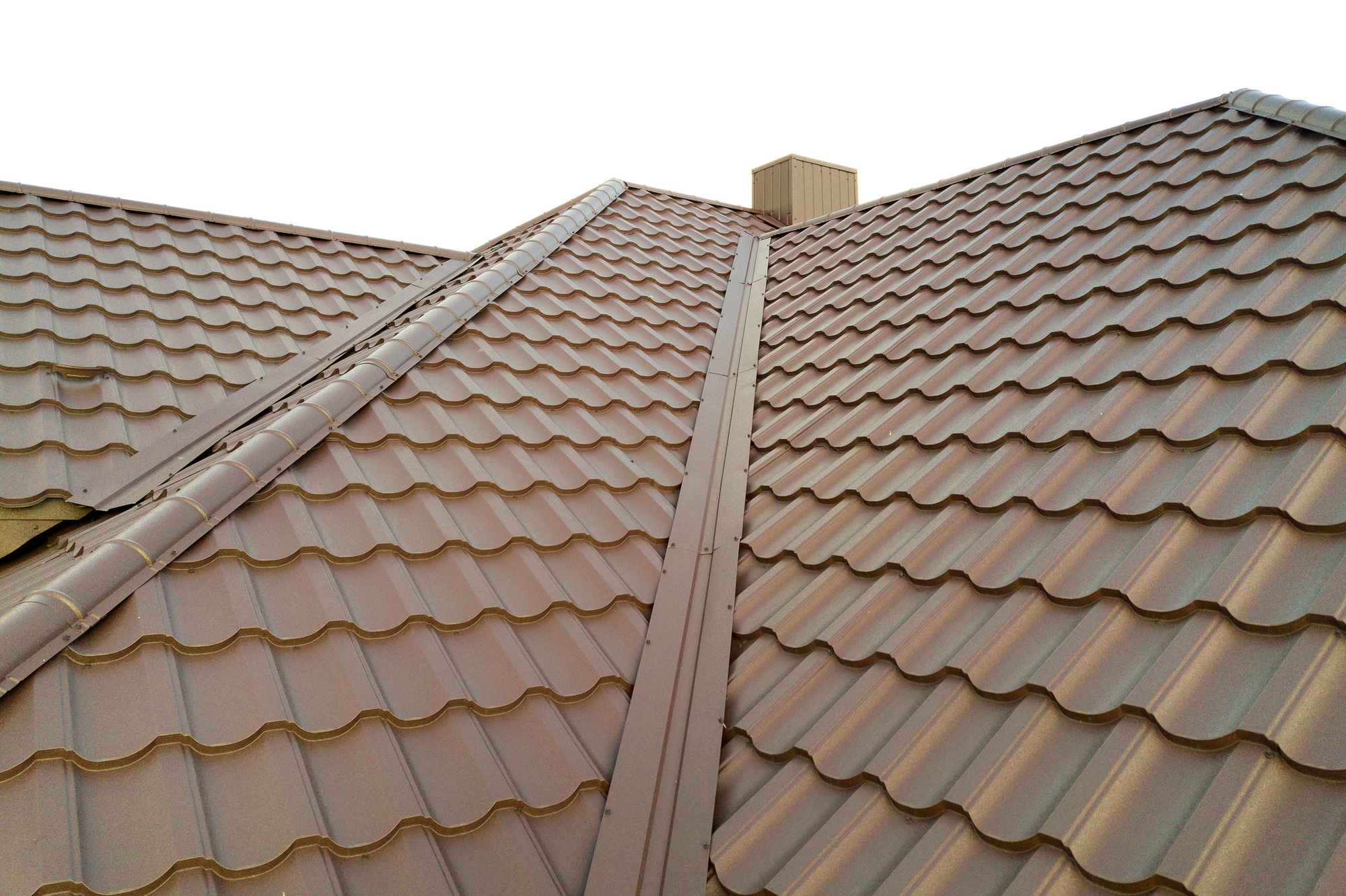 Detail of house roof structure covered with brown metal tile sheets.